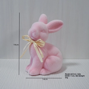 Pink flocked Easter rabbit with dimensions 19x14x11cm and straw bow on wooden background