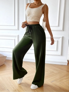 Detail of loose fit dark green wide-leg trousers with drawstring waist on model