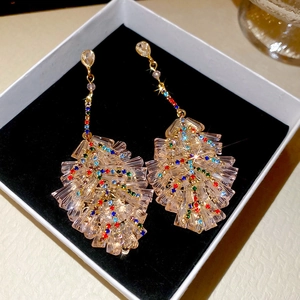 Macro shot of long crystal leaf earrings with colorful rhinestones in a white gift box