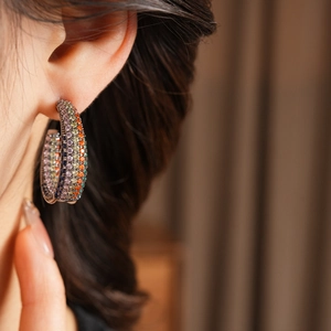 Macro detail of silver C-hoop earrings featuring multi-color micro-set zircon stones