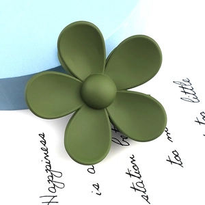 Close-up of matte dark green flower hair claw clip on decorative blue background
