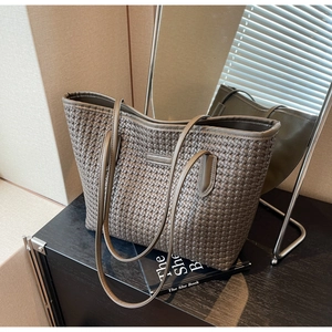 Close-up of the woven leather texture and shoulder straps on a grey tote bag