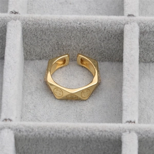 Golden irregular polygon open ring with engraved smiley face patterns on metal surface