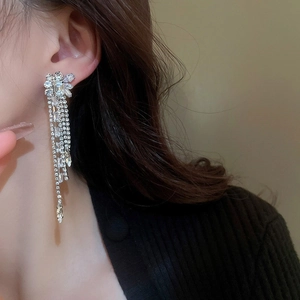 Gros plan de boucles d'oreilles clips à pompons en strass argentés sur un mannequin