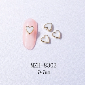 Close-up of heart-shaped nail art charm with gold metal edge and white inlay 7x7mm