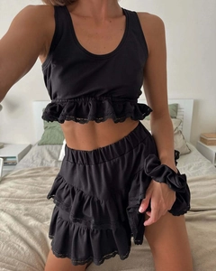 Detailed lace trim on black two-piece set featuring ruffled crop top and mini skirt