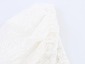 Gros plan d'un crop top blanc en dentelle avec broderies florales et poignets élastiques