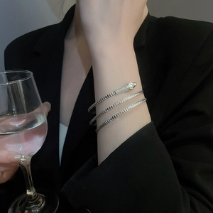 Detail of silver snake spiral bracelet with textured scales worn in a high-end social setting