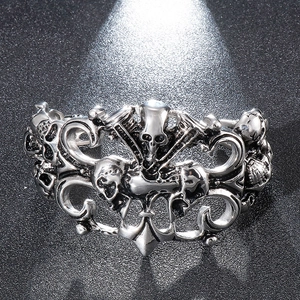 Macro shot of silver stainless steel cuff with carved skulls and hollow baroque patterns