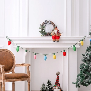 Colorful knitted Christmas bulb garland hanging on a festive white fireplace mantel