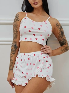 Detail der weißen Rippstrick-Pyjamas mit Herzmuster, Rüschensaum und kleiner Schleife