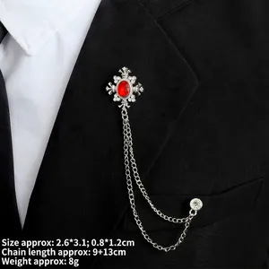 Detail of vintage silver cross brooch with red gemstone on black suit collar