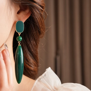 Close-up of elegant green malachite drop earrings with gold metal links on a female model