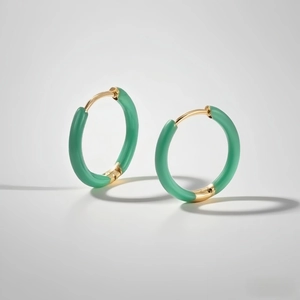 Detail of gold titanium steel hoop earrings with translucent emerald green enamel inlay