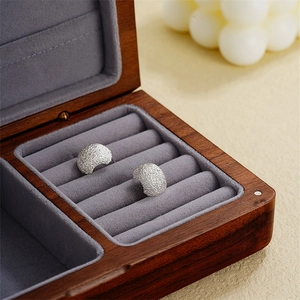 Macro detail of silver frosted crescent earrings on grey velvet jewelry box