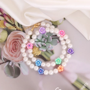 Bohemian double-layer necklace with white pearls and colorful flower beads on silk background