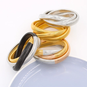 Primer plano de pulseras de serpiente apiladas en oro, plata y oro rosa