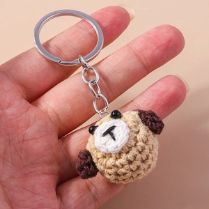 Detail of a handmade crochet puppy keychain with brown ears and silver metal ring