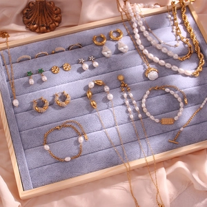 Elegant gold pearl jewelry set including necklace, bracelet, and earrings on pink silk