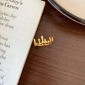 Detailed top view of gold crown ring with unique fluid dripping design on wood background