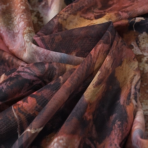 Macro shot of breathable mesh fabric with red and orange abstract tie-dye print patterns