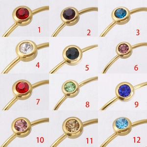 Twelve colors of minimalist gold plated stainless steel birthstone rings in a grid view