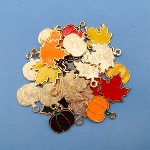 Macro shot of maple leaf and pumpkin enamel pendants for DIY autumn jewelry making