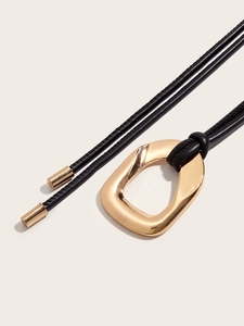 Macro shot of minimalist black leather cord belt with a polished gold geometric metal buckle
