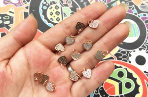 Mini heart pendant in rose gold with white zircon stones held in hand for scale