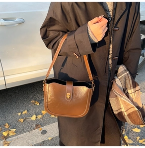 Close-up of caramel brown saddle bag with glossy leather texture and golden metal lock