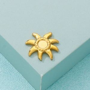 Close-up of a polished gold sun pendant for jewelry making on a blue geometric base