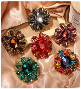 Detail view of flower crystal brooches in six colors on champagne silk background