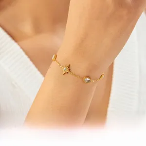 Detail shot of a gold-plated stainless steel chain bracelet with star and oval charms