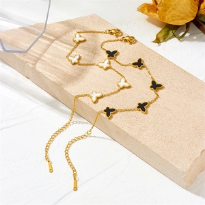 Double-layered gold butterfly necklace with black and white shells on a stone pedestal