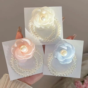 Detail of camellia flower hair ties with pearls in cream, pink, and light blue colors
