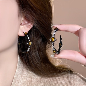 Detail view of vintage C-shape earrings with tiger eye stone and crystals on model
