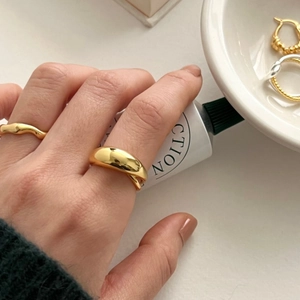 Detailed view of wide curved cross ring in gold finish on female index finger
