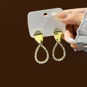 Detail view of gold pear-shaped drop earrings with micro-pave white cubic zirconia