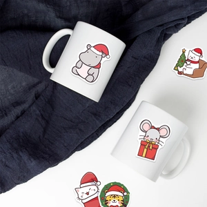 Christmas cartoon animal stickers on a white mug with a festive blue fabric background