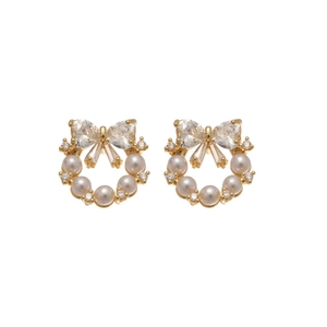 Elegant gold bow earrings with white pearls and zircons on white background