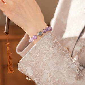 Macro detail of purple amethyst beads and silver clover charm on a vintage style bracelet