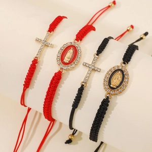 Detail of red and black braided bracelets with crystal cross and Virgin Mary charms