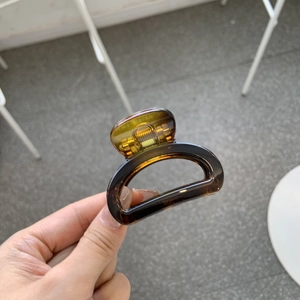 Detailed close-up of tortoise shell pattern hair claw clip in amber brown finish