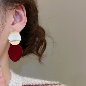Détail macro de boucles d'oreilles vintage en velours rouge foncé avec disque métal doré poli