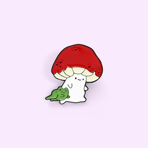 Cartoon mushroom sprite and small green frog enamel pin brooch with smiling face detail