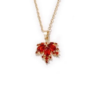 Elegante collana a foglia d'acero dorata con zirconi rossi su uno sfondo bianco pulito