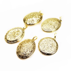 Detail of gold-plated oval locket pendants with intricate floral and vine engravings