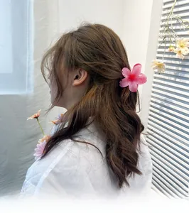 Detailed view of pink flower hair claw clip with gradient petals on model hair