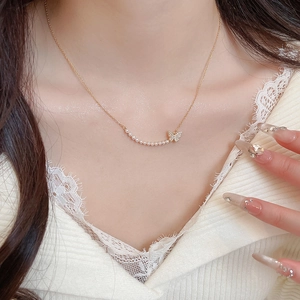 Close-up of 18k gold butterfly necklace with pearls and zircons on a female model