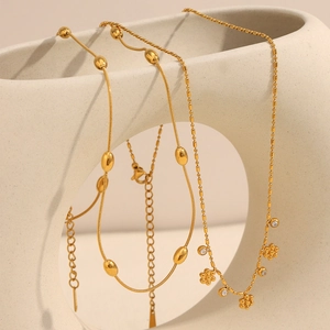Gros plan sur l'ensemble collier en maille serpent dorée 18 carats avec pendentif fleur